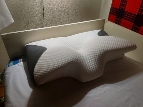 Customer's Gerincbarát Anatólmiai Párna on a bed, showing its ergonomic white and gray foam design.