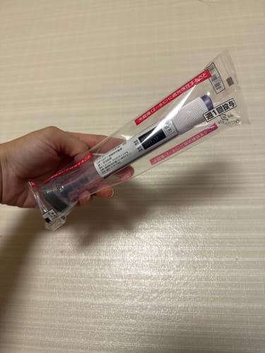 レビューアの手で持たれた、透明なビニール袋に入った注射器型のelifeギフトカードの包装。