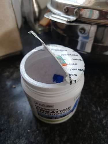Customer's opened tub of Wellcore Creatine Monohydrate, showing the white packaging and torn safety seal.