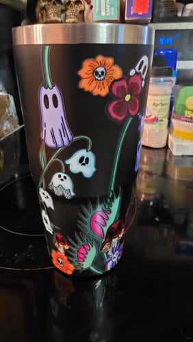 Customer's Mystery To-Go Buddy tumbler featuring a black base with colorful ghost and botanical floral illustrations.
