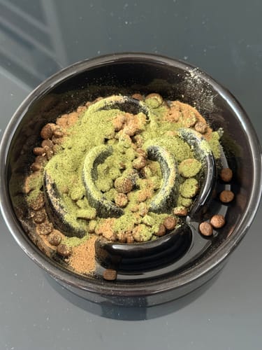 Reviewer's ProClean™狗狗天然潔牙護齒配方粉末撒在寵物餵食碗中的飼料上。