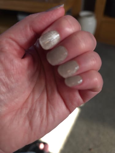 Customer's hand showing Holy Gels Starter Kit nails in a shimmering beige color after application.