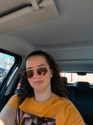 Cliente usando os Óculos de Sol Icon com armação dourada dentro de um carro.
