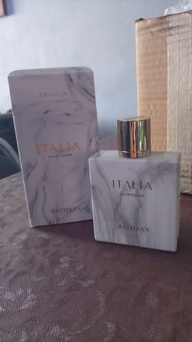 Customer's Perfume Rayhaan Italia bottle and white marble box on a brown surface.