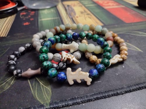 Reviewer's five colorful Shark Week Bracelets with hammerhead shark charms arranged on a patterned surface.