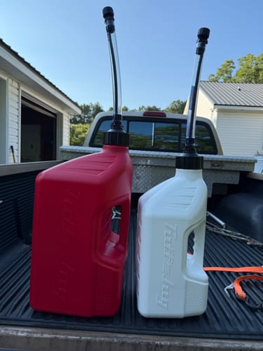 Customer's red and white Tuff Jug utility containers sitting in the back of a truck bed.