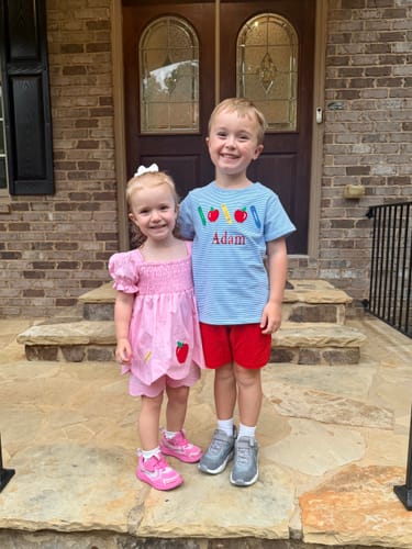 Customer's child wearing the You Rule Pink Hannah Short Set next to sibling on a stone porch.