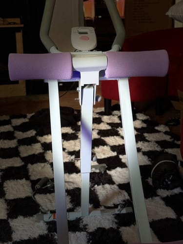 Reviewer's Dual-Track Ab Machine featuring two light purple padded arm rests and an LCD monitor in a room.