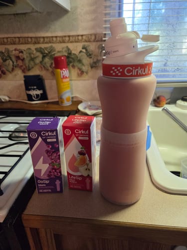 Customer's LifeSip Fruit Punch and Grape GoSip cartridges next to a filled Cirkul water bottle on a kitchen counter.