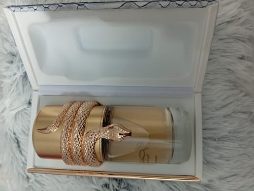 Customer's Lattafa Musamam White Intense perfume bottle with its unique snake design, placed inside the open box.