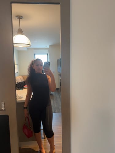 Customer's black Naked Sleeveless Capri Jumpsuit, worn while holding a red purse in a room reflection.
