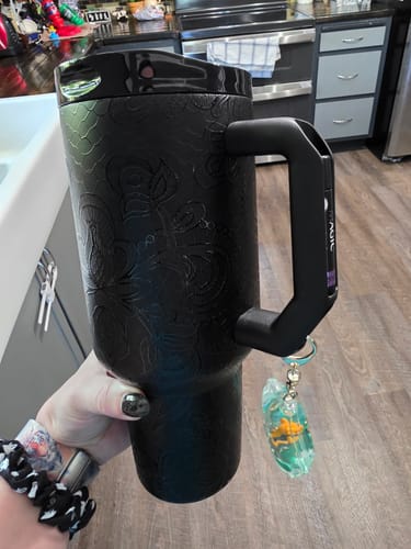 Reviewer's black lace-patterned Thicc Buddy mug held in hand, featuring a keychain hanging from the handle.