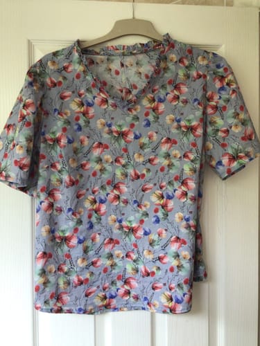 Customer's Whimsy Garden Cotton Lawn blouse featuring a floral print, hanging on a hanger.