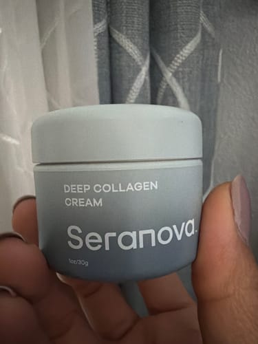 Reviewer's hand holding a gray jar of Deep Collagen Cream.