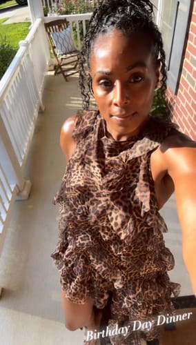 Customer's chiffon print asymmetric ruffle dress showing leopard print and layered ruffles, standing on a porch.