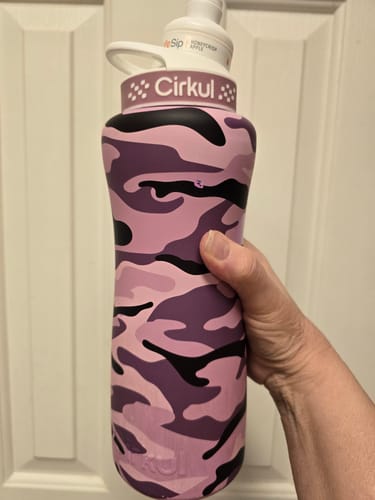 Customer's hand holding a pink and purple camo Cirkul water bottle with a Honeycrisp Apple flavor sip cartridge.