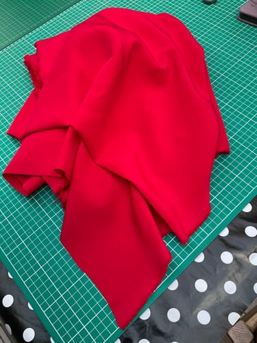 Customer's crimson red polyester fabric draped over a green cutting mat.