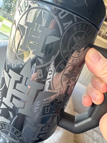 Customer's hand holding the black Thicc Buddy 40oz Houston Astros mug, showing the repeating team logo pattern.
