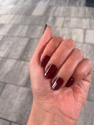 Customer's hand showing applied Ruby CatEye UV Gel nail wraps with a shiny, ruby-red finish.