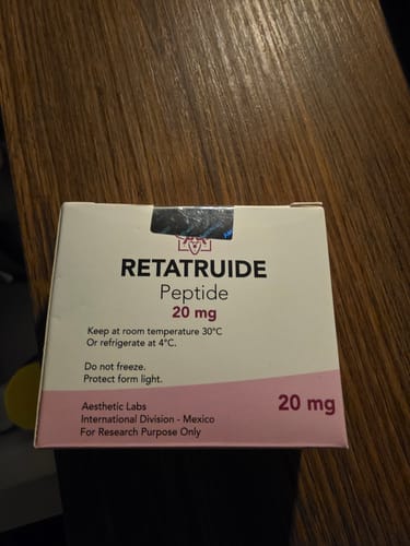 Customer's Aesthetic Labs Retatruide Peptide 20mg packaging box on a dark wooden surface.