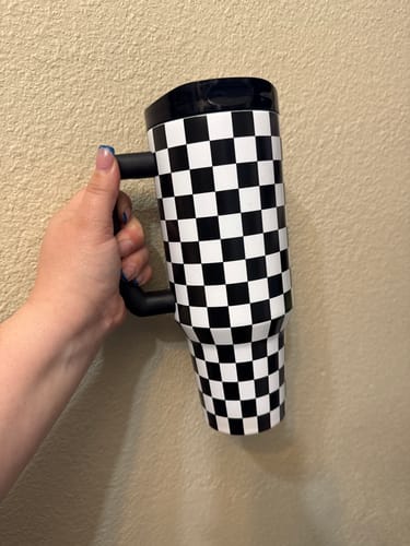 Customer's hand holding a black and white checkered Thicc Buddy 40oz insulated mug.