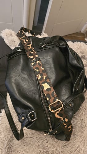 Customer's Correa Strap Cartera Diseño Animal Print instalada en un bolso negro sobre una manta peluda.