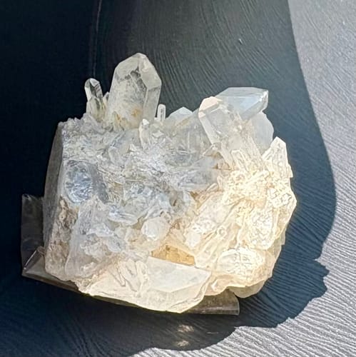 Customer's VIP Crystal Club quartz crystal cluster resting on a car dashboard in sunlight.