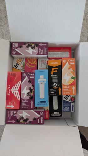 Customer's cardboard box filled with an assortment of colorful Cirkul flavor cartridges.