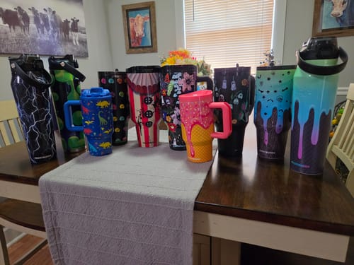 Reviewer's collection of colorful Thicc Buddy mugs arranged on a wooden table.