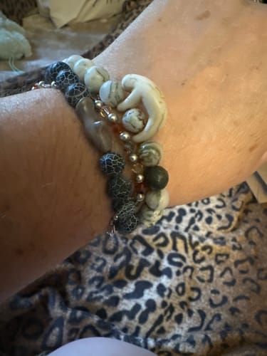 Customer's hand wearing stacked beaded Voyage Bracelets including a charm shaped like a hammerhead shark.