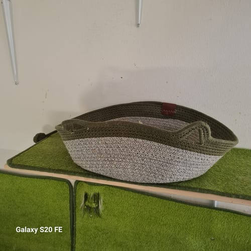 Kunden Fellnest Katzenkorb in olivgrün und beige aus geflochtenem Seil auf einer grünen Oberfläche.