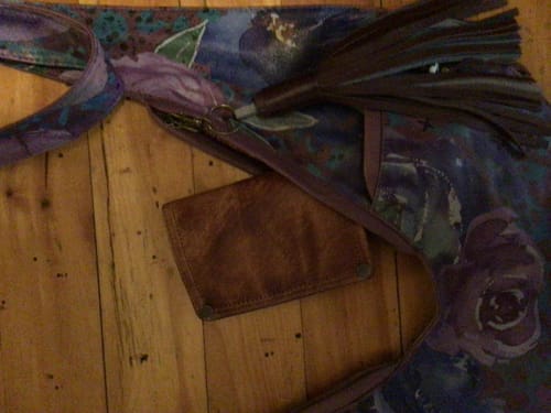 Customer's brown leather Vintage Pure Color Wallet tucked inside a patterned purple purse on a wooden surface.
