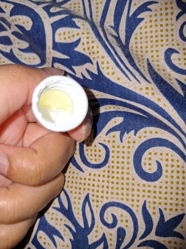 Customer's hand holding the open, partially empty cap of Advance Lip Pigmentation Cream.
