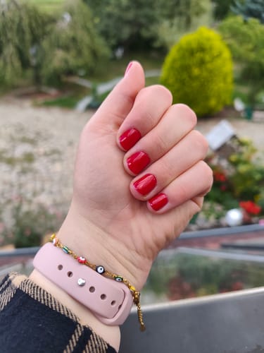 Customer's Hand mit intensiv rotem UV Nagellack No. 7, perfekt aufgetragen mit glänzendem Finish.