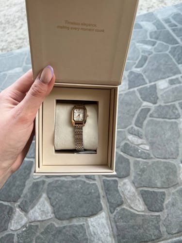 Customer's Isabell Petite gold and silver watch inside its open beige branded packaging box