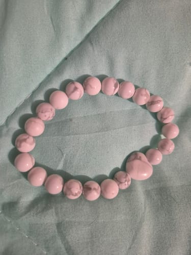 Customer's VIP Crystal Club white beaded bracelet lying on a soft, light green fabric surface.