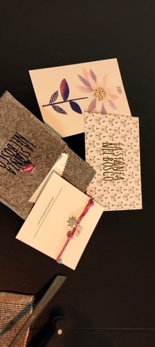 Customer's Stella alpina d'inverno bracelet, with packaging, cards and a felt pouch on a dark surface.