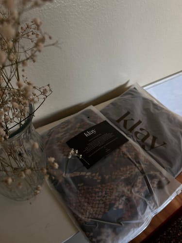 Customer's Klay hijabs in branded plastic packaging with a decorative plant in a glass vase nearby.