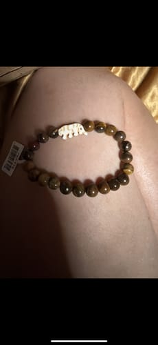Customer's Prowl Bracelet featuring brown stone beads and a tiger charm, worn on a person's leg.