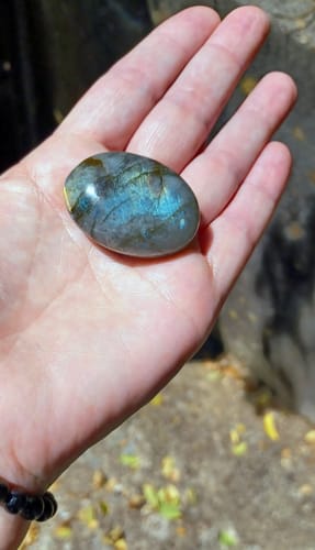 Customer's smooth Labradorite Moonstone held in the palm of a hand, showing blue iridescent shimmer.