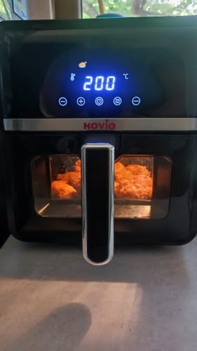 Reviewer's black Novio StonePro air fryer showing 200 degrees on the digital display while cooking food.