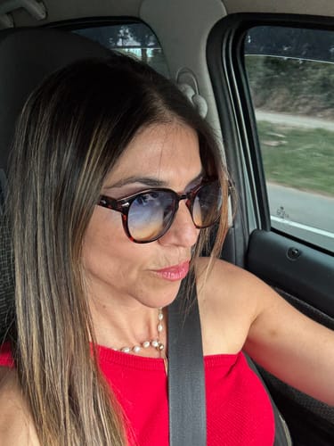 Customer's Óculos de Sol Jurerê com armação escura em um rosto, visto dentro de um carro.