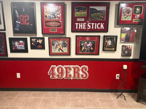 Customer's San Francisco 49ers metal wall art mounted on a red wall in a man cave filled with sports memorabilia.