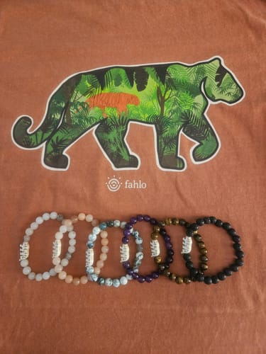 Customer's Prowl T-Shirt in rust orange with a tiger print, displayed above several beaded tiger bracelets.