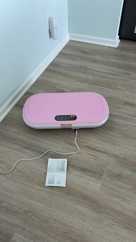 Customer's pink CV40 Curved vibration plate on a wood floor with a manual nearby.