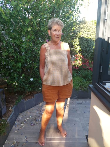 Reviewer's blouse Florence en seersucker vichy ocre portée avec un short uni dans un jardin.