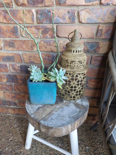 Customer's Rueben lantern in weathered rust metal, sitting on a wooden stool next to a succulent pot
