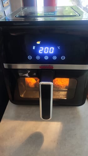 Customer's black Novio StonePro air fryer during use with the internal light showing food through the window.