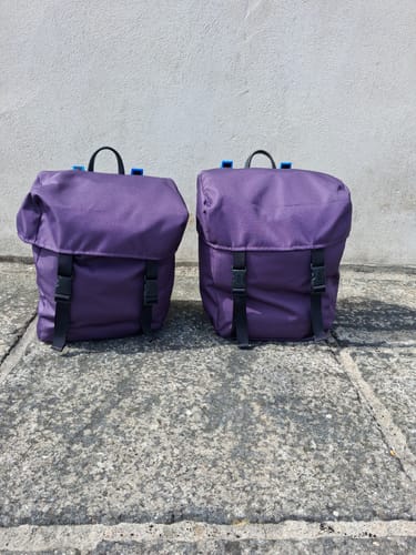 Customer's two purple Outdoor Water Resistant Canvas Fabric panniers crafted for a bicycle, sitting on paving stones.