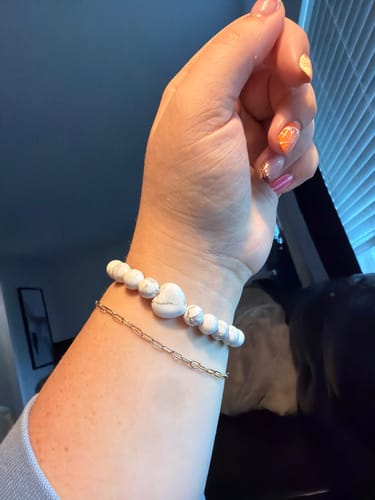 Customer's VIP Crystal Club white howlite heart-shaped bead bracelet worn on a wrist alongside a thin gold chain.